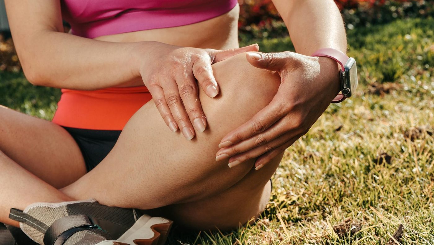 Person sitting on grass holding the knee