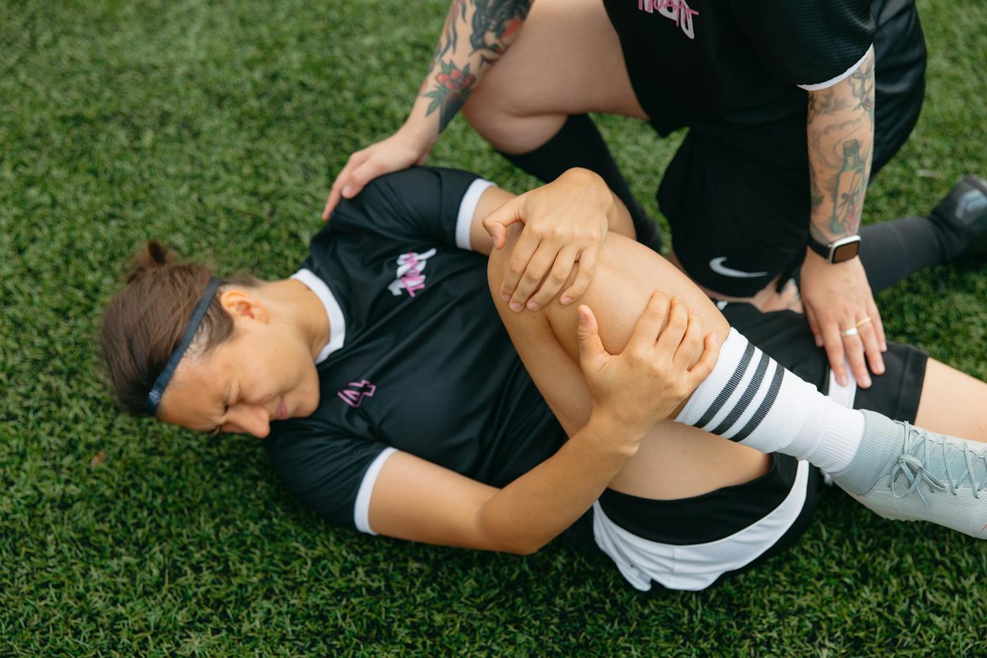 Soccer player holding an injured knee on grass